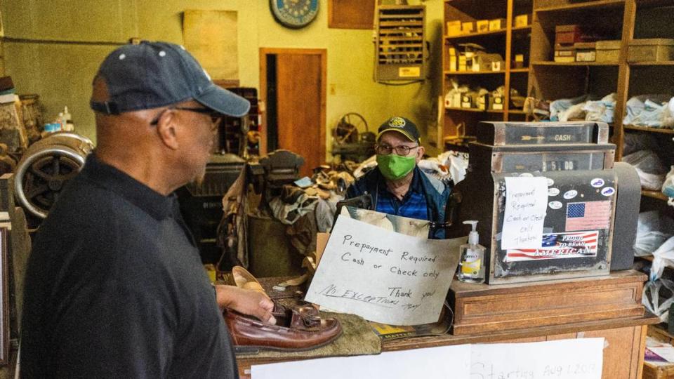 Tony Likirdopulos, right, chats with customer John Harris, left, who had come to collect his shoes from Tony’s shop, Tony’s Shoe Repair. Tony plans to retire after 54 years of operating his business downtown on West Short street. October 21, 2021.