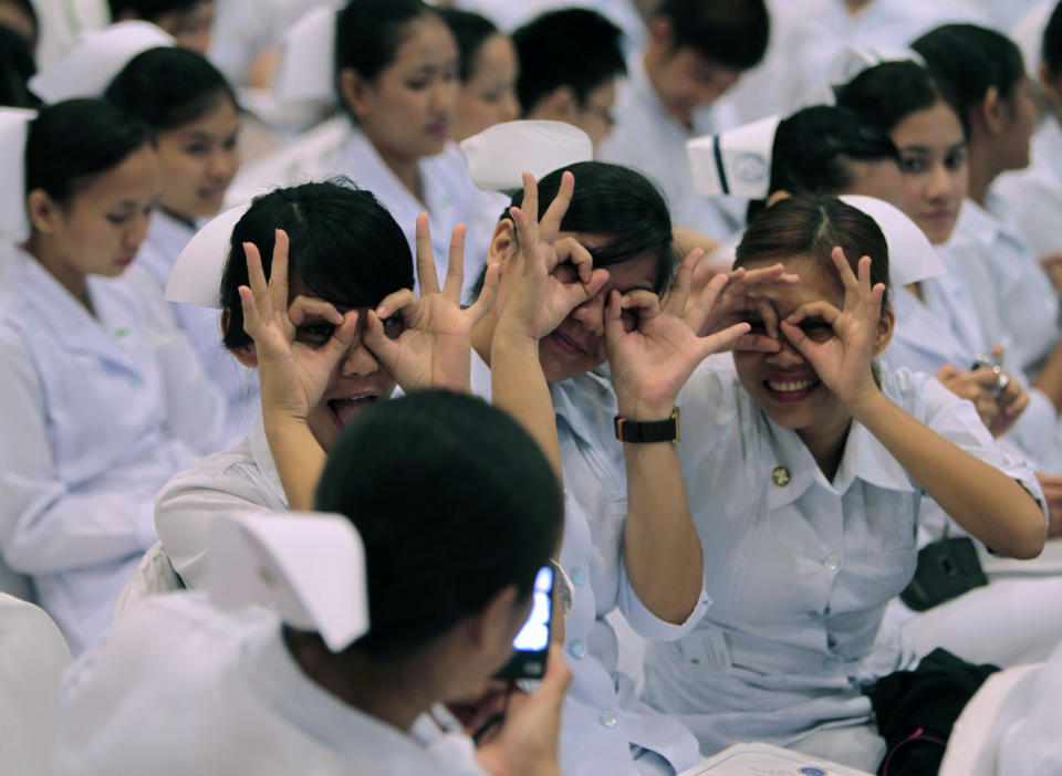 FILE PHOTO: Newly graduated nurses gesture while having their picture taken by a friend before the oath taking ceremony of the professional nurses inside a mall in Manila September 20, 2010. REUTERS/Romeo Ranoco