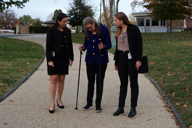 <p>Courtesy of the Wexton Office</p> Jennifer Wexton stands with aides, using walking poles as her mobility declines from PSP