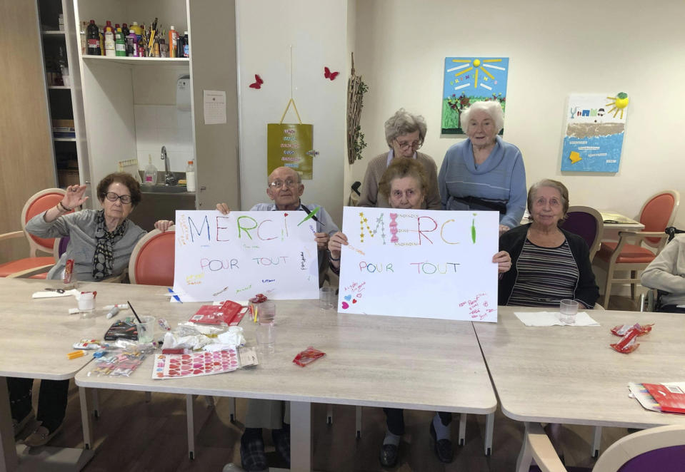 In this photo provided by the Vilanova nursing home, residents show posters reading "Thank you for everything" on April 27 2020 in Corbas, central France. The nursing staff of the care home in Lyon decided 45 days ago that rather than lock residents in their rooms as the government urged, the staff would lock themselves in the home with residents so as not to deprive the elderly of their freedom. The home has had zero virus cases so far. (Valerie Martin via AP)