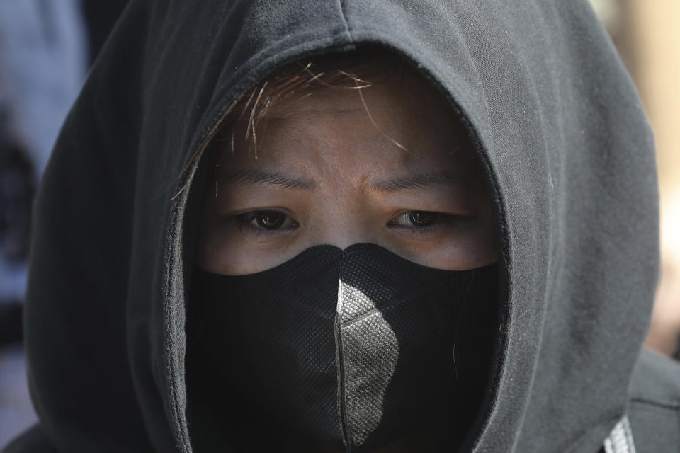 A protester wears a face mask during a rally for students and elderly pro-democracy demonstrators in Hong Kong, Saturday, Nov. 30, 2019. Hundreds of Hong Kong pro-democracy activists rallied Friday outside the British Consulate, urging the city's former colonial ruler to emulate the U.S. and take concrete actions to support their cause, as police ended a blockade of a university campus after 12 days. (AP Photo/Ng Han Guan)