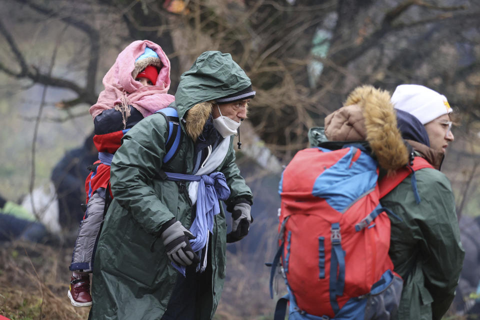 Migrants from the Middle East and elsewhere, one carrying a child, gather at the Belarus-Poland border near Grodno, Belarus, Monday, Nov. 8, 2021. Poland increased security at its border with Belarus, on the European Union's eastern border, after a large group of migrants in Belarus appeared to be congregating at a crossing point, officials said Monday. The development appeared to signal an escalation of a crisis that has being going on for months in which the autocratic regime of Belarus has encouraged migrants from the Middle East and elsewhere to illegally enter the European Union, at first through Lithuania and Latvia and now primarily through Poland. (Leonid Shcheglov/BelTA via AP)