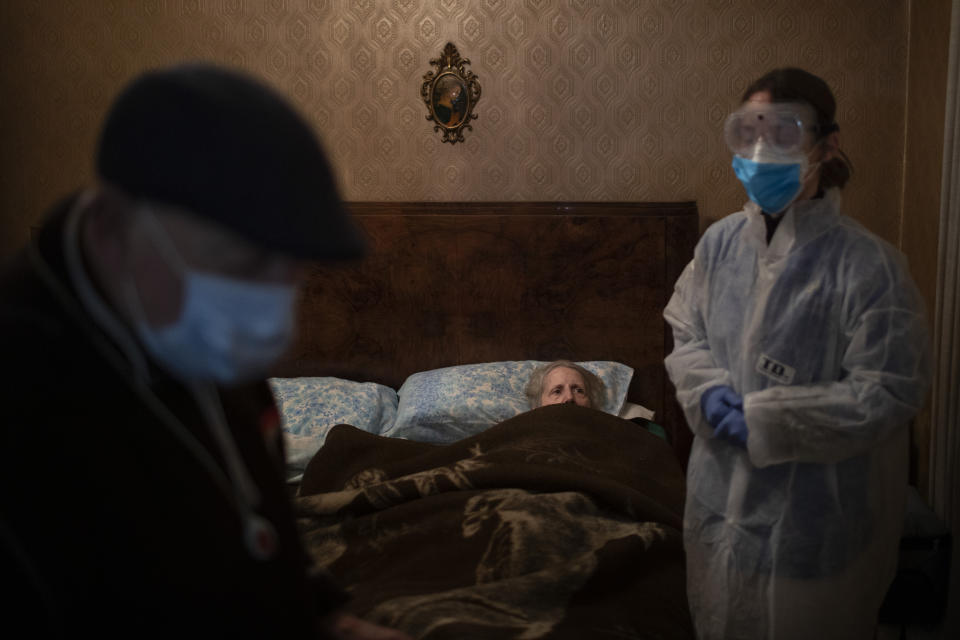 Josefa Ribas, 86, who is bedridden, looks at nurse Alba Rodriguez as Ribas’ husband, Jose Marcos, 89, stands by in their home in Barcelona, Spain, March 30, 2020, during the coronavirus outbreak. Ribas suffers from dementia, and Marcos fears for them both if the virus enters their home. "If I get the virus, who will take care of my wife?" (AP Photo/Emilio Morenatti)