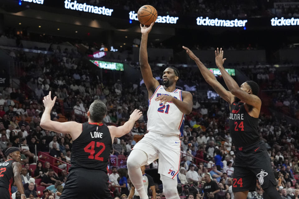 Philadelphia 76ers center Joel Embiid (21) aims a three point shot as Miami Heat forwards Kevin Love (42) and Haywood Highsmith (24) defend during the first half of an NBA basketball game, Thursday, April 4, 2024, in Miami. (AP Photo/Marta Lavandier)