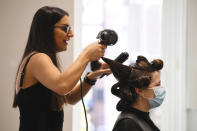 Hairdresser Caroline Shamoon of Joey Scandizzo Salon works on a client's hair in Melbourne, Friday, Oct. 22, 2021. Melbourne, Australia’s most populous city after Sydney, came out of 77 days of lockdown on Friday after Victoria state reached a benchmark of 70% of the target population fully vaccinated. (James Ross/AAP Image via AP)