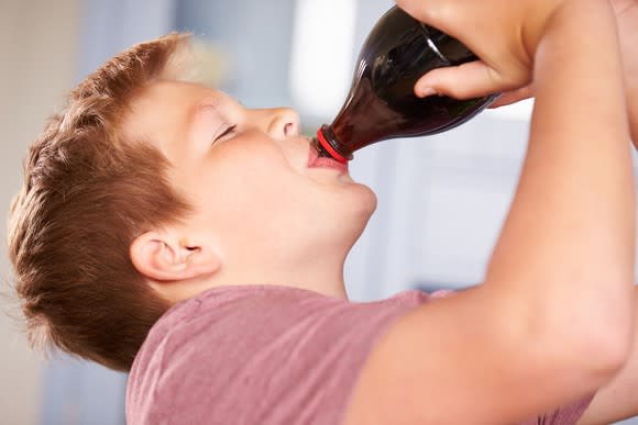 Boy drinking bottle of soda