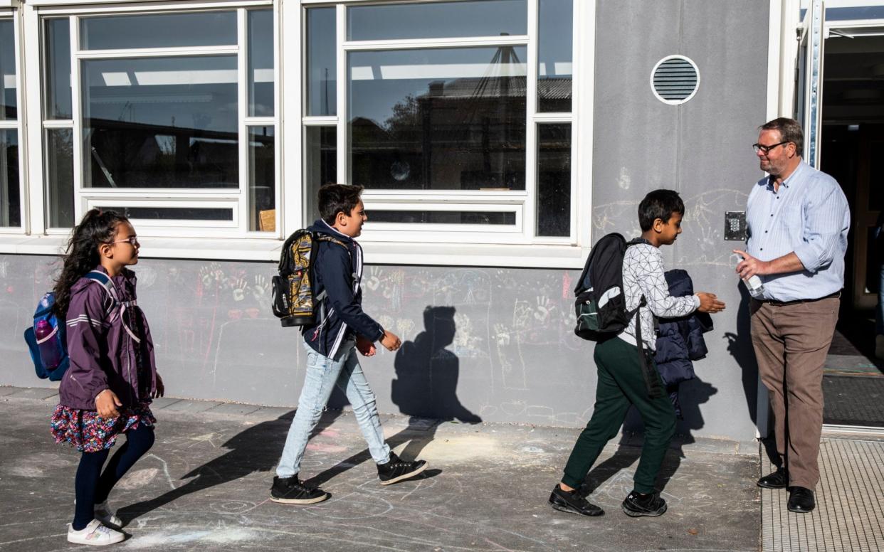 A Danish headteacher hands out hand sanitiser to his pupils on arrival at school - Ritzau Scanpix