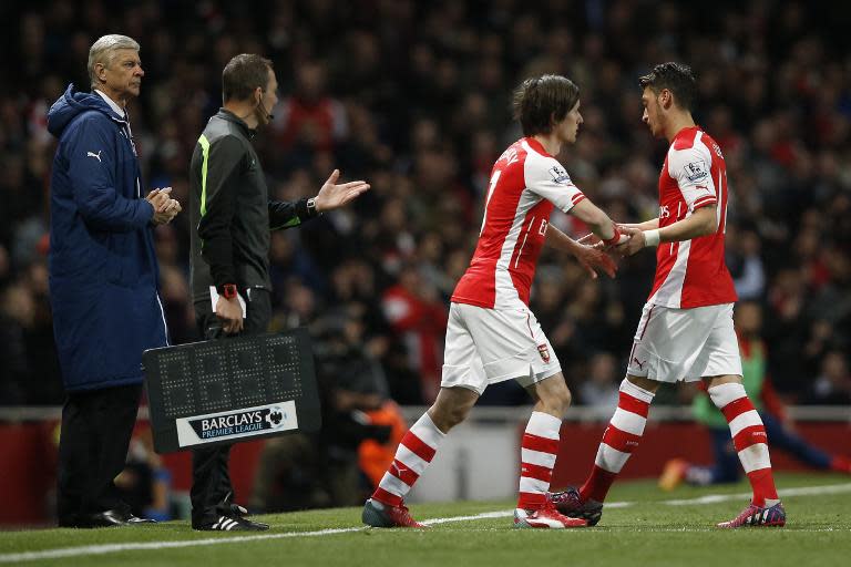 Arsenal's Mesut Ozil (R) is substituted and replaced by Tomas Rosicky as manager Arsene Wenger (L) looks on, during their English Premier League match against Sunderland, at the Emirates Stadium in London, on May 20, 2015