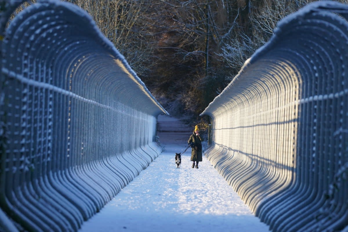 A woman walks her dog through snow over Castleside Viaduct in Durham. Parts of the UK are being hit by freezing conditions with the UK Health Security Agency (UKHSA) issuing a Level 3 cold weather alert covering England until Monday and the Met Office issuing several yellow weather warnings for snow and ice in parts of the UK over the coming days. Picture date: Friday December 9, 2022. (PA Wire)