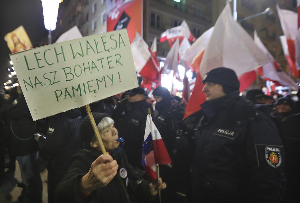 An anti-government activist carries a placard which reads "Lech Walesa our hero. We remember!"" as she marches past pro-government activists during a demonstration to mark the 35th anniversary of the marshal law in Warsaw, Poland, Tuesday, Dec. 13, 2016. (AP Photo/Czarek Sokolowski)