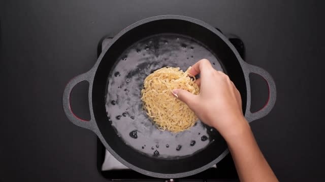 Adding mee pok noodles to boiling water