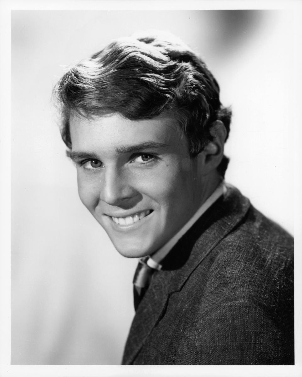 Young Jay North smiles at the camera while wearing a suit 