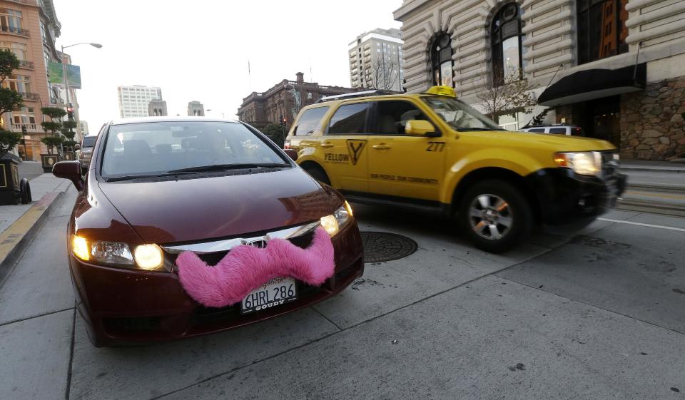 In this Jan. 4, 2013 photo, Lyft driver Nancy Tcheou waits in her car after dropping off a passenger as a taxi cab passes her in San Francisco. Fed up with traditional taxis, city dwellers are tapping their smartphones to hitch rides from strangers using mobile apps that allow riders and drivers to find each other. Internet-enabled ridesharing services such as Lyft, Uber and Sidecar are expanding rapidly in San Francisco, New York and other U.S. cities, billing themselves as a high-tech, low-cost alternative to cabs. (AP Photo/Jeff Chiu)