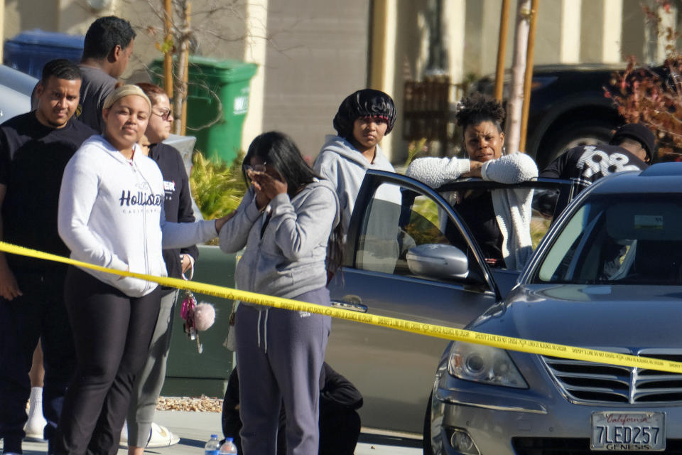 Neighbors react near a home where five bodies were found in the city of Lancaster in the high desert Antelope Valley north of Los Angeles, Monday, Nov. 29, 2021. A Los Angeles County Sheriff's Department statement says deputies found a woman, a girl and three boys with gunshot wounds and paramedics pronounced them dead at the scene. The department says the children's father showed up at the Lancaster sheriff's station and was arrested on suspicion of five murders after being interviewed by detectives. (AP Photo/Ringo H.W. Chiu)