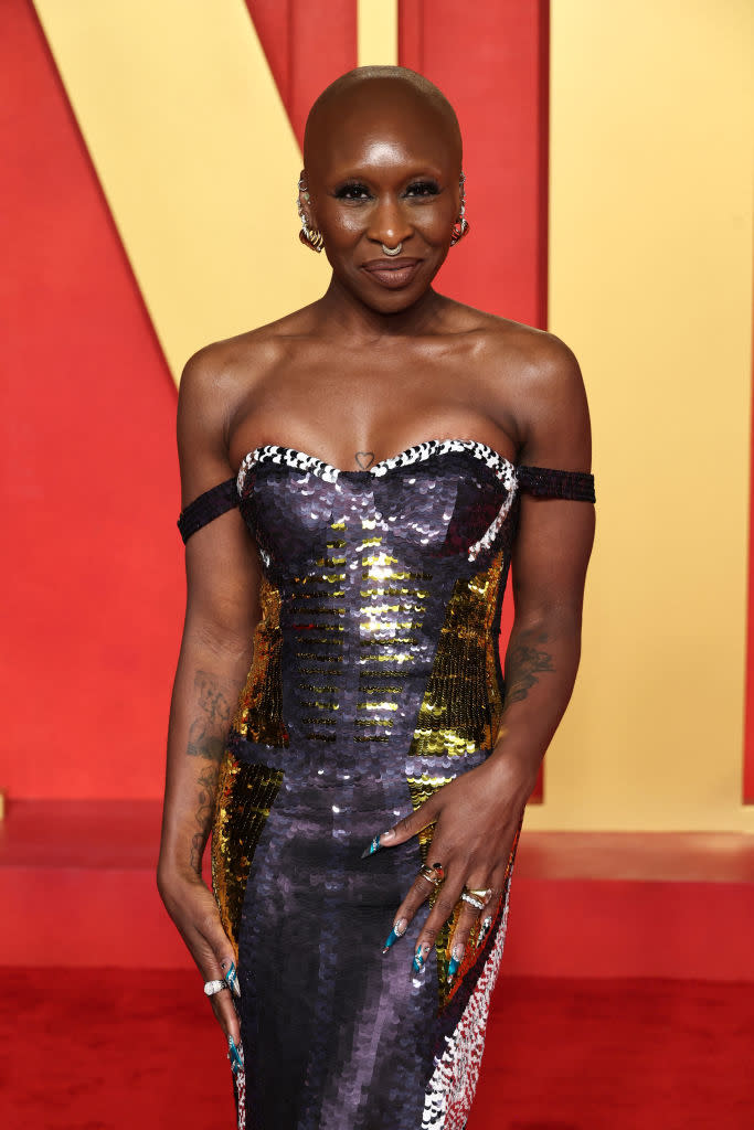 Cynthia Erivo poses on the red carpet in a sequined off-shoulder dress with her hands on her hips