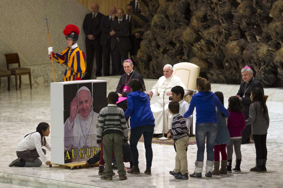 Children complete a puzzle depicting Pope Francis in the Vatican