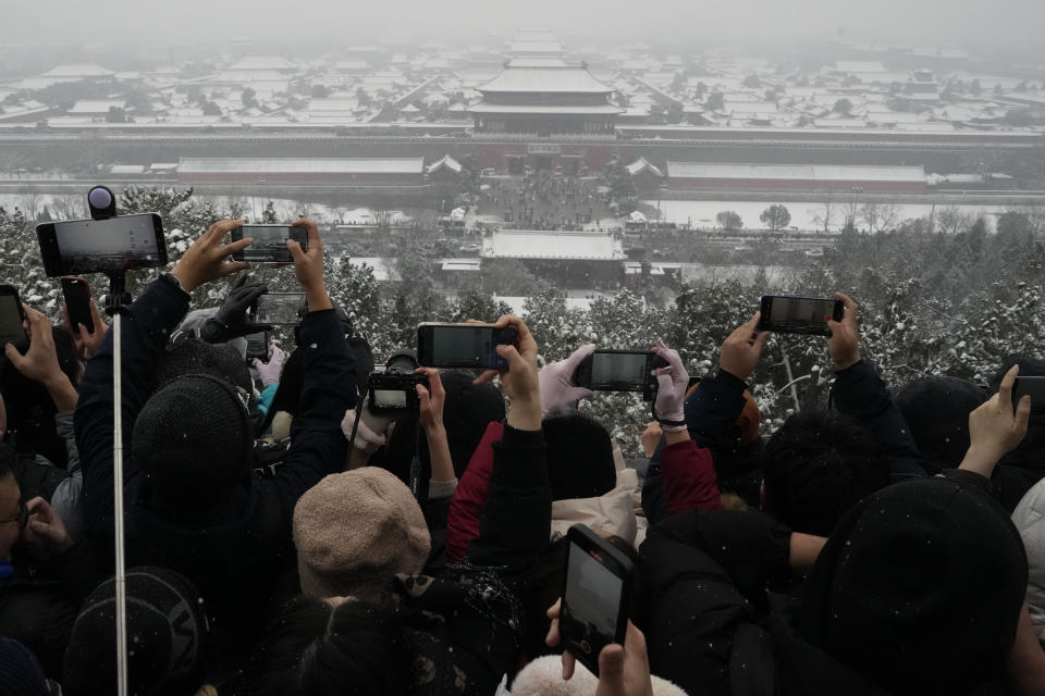 Residents fight for to get a shot of the snow covered Forbidden City from a hilltop pavilion in Jingshan Park in Beijing, Wednesday, Dec. 13, 2023. (AP Photo/Ng Han Guan)