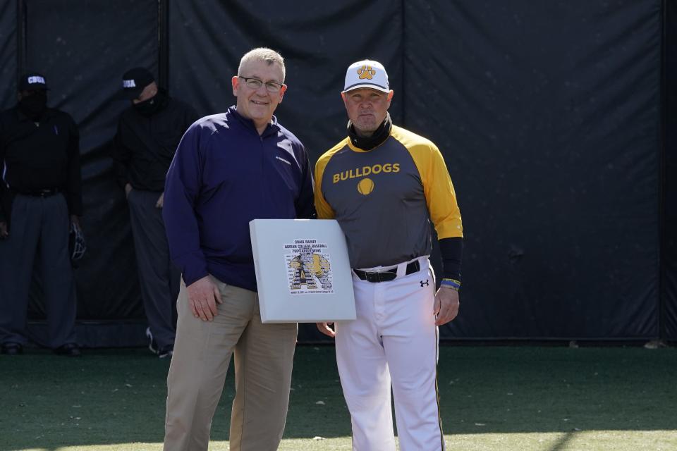 Adrian College athletic director Mike Duffy presents head baseball coach Craig Rainey with a base to honor his 700th win in 2021.