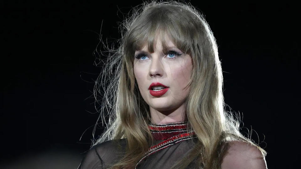 Taylor Swift looks up in a black and red costume from her Eras Tour