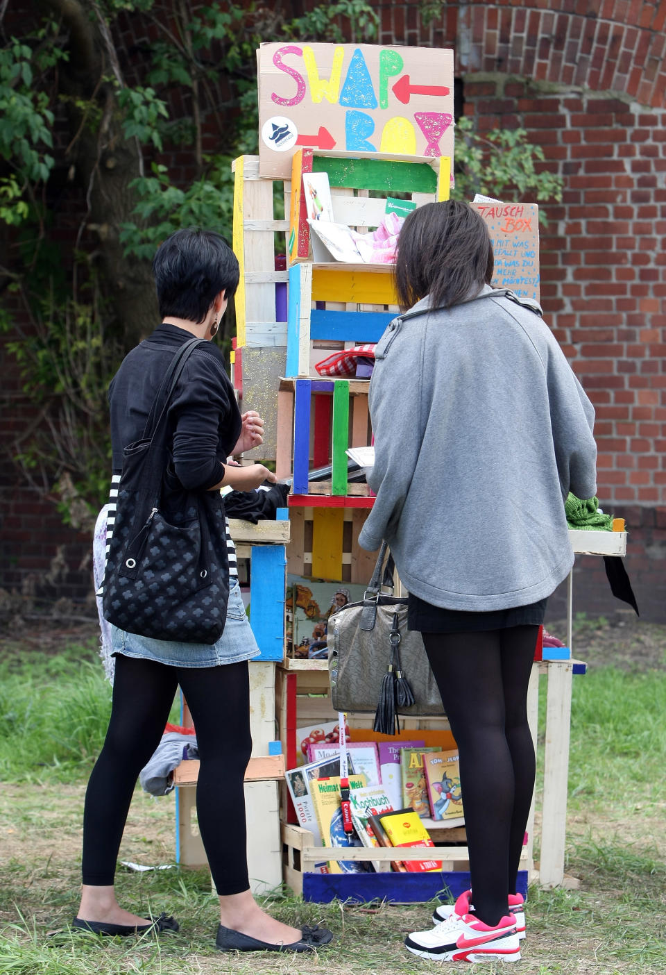 BERLIN, GERMANY - JULY 21: Attendees browse through items at a "swap box," where visitors can take items in exchange for leaving others, at the second annual Hipster Olympics on July 21, 2012 in Berlin, Germany. With events such as the "Horn-Rimmed Glasses Throw," "Skinny Jeans Tug-O-War," "Vinyl Record Spinning Contest" and "Cloth Tote Sack Race," the Hipster Olympics both mocks and celebrates the Hipster subculture, which some critics claim could never be accurately defined and others that it never existed in the first place. The imprecise nature of determining what makes one a member means that the symptomatic elements of adherants to the group vary in each country, but the archetype of the version in Berlin, one of the more popular locations for those following its lifestyle, along with London and Brooklyn, includes a penchant for canvas tote bags, the carbonated yerba mate drink Club Mate, analogue film cameras, asymetrical haircuts, 80s neon fashion, and, allegedly, a heavy dose of irony. To some in Berlin, members of the hipster "movement" have replaced a former unwanted identity in gentrifying neighborhoods, the Yuppie, for targets of criticism, as landlords raise rents in the areas to which they relocate, particularly the up-and-coming neighborhood of Neukoelln. (Photo by Adam Berry/Getty Images)