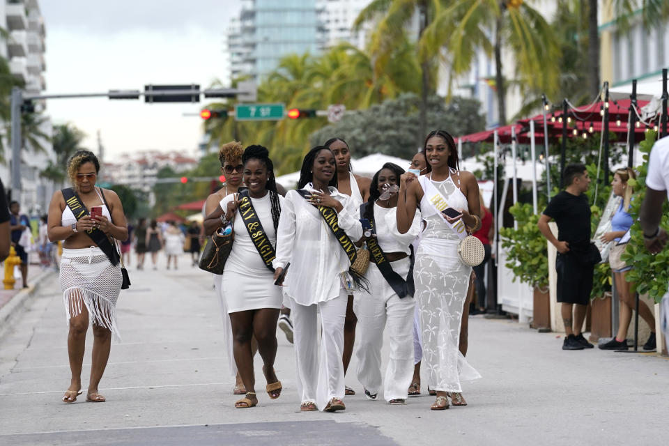 A group of people in a bridal party from Houston, Tx. walk along Ocean Drive, Friday, Sept. 24, 2021, in Miami Beach, Fla. For decades, this 10-block area has been one of the most glamorized spots in the world, made cool by TV shows like Miami Vice, where the sexiest models gathered at Gianni Versace's ocean front estate and rappers wrote lines about South Beach's iconic Ocean Drive. (AP Photo/Lynne Sladky)
