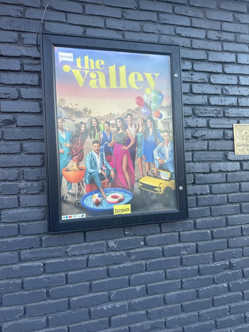 Promotional poster for the show "The Valley" with cast members posing around a yellow car and a swimming pool