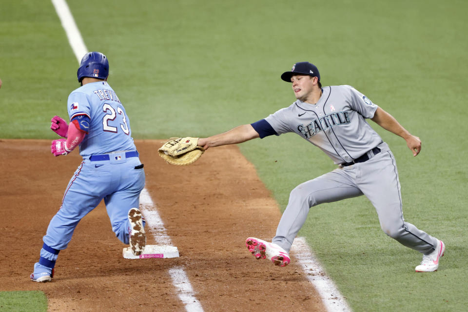 Texas Rangers catcher Jose Trevino (23) evades a tag by Seattle Mariners first baseman Evan White (12) as he makes it safely to first during the fifth inning of a baseball game Sunday, May 9, 2021, in Arlington, Texas. (AP Photo/Michael Ainsworth)