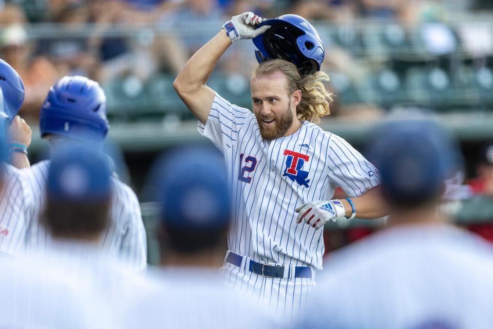 Louisiana Tech utility Philip Matulia (12) celebrates scoring against DBU during an NCAA baseball game on Friday, June 3, 2022, in Austin, Texas. (AP Photo/Stephen Spillman)