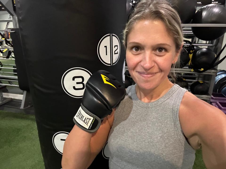 Author Terri Peters with a boxing glove on smiling in front of a punching bag