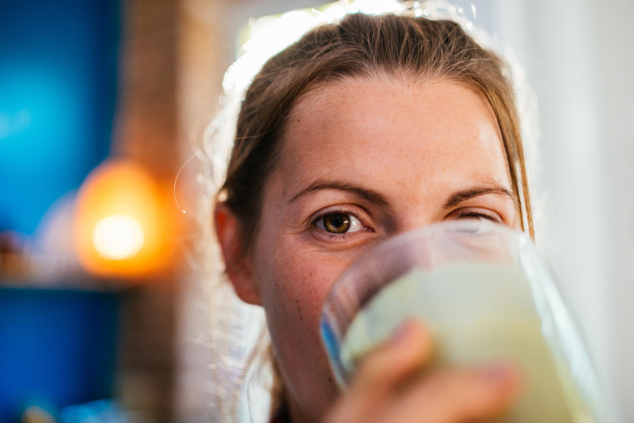 Woman enjoying fresh smoothie at home, close-up.