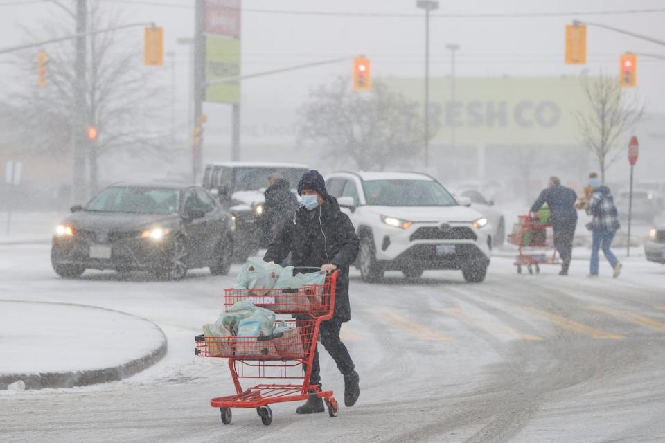 Shoppers navigate icy conditions and blowing snow at an east-end Toronto grocery store parking lot on Dec. 23, 2022.
