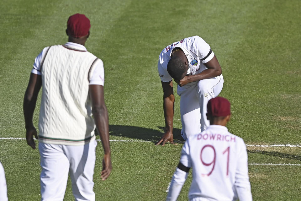 The West Indies Kemar Roach, centre, kneels as he celebrates the wicket of New Zealand's Tom Latham during play on day one of the first cricket test against New Zealand in Hamilton, New Zealand, Thursday, Dec. 3, 2020. (Andrew Cornaga/Photosport via AP)