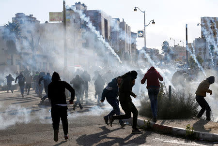 Palestinian protesters run from tear gas fired by Israeli troops during clashes at a protest against U.S. President Donald Trump's decision to recognize Jerusalem as the capital of Israel, near the Jewish settlement of Beit El, near the West Bank city of Ramallah December 7, 2017. REUTERS/Mohamad Torokman