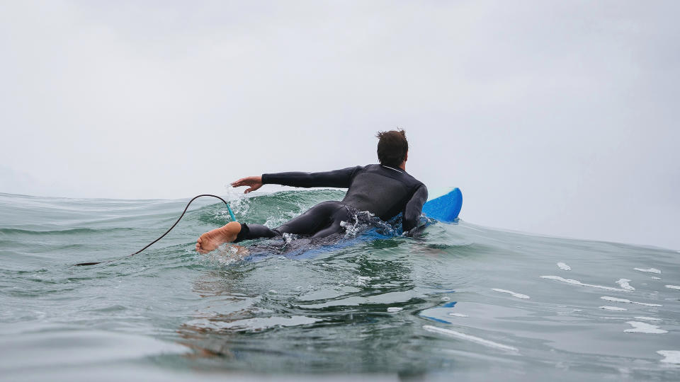 Person surfing/paddle boarding wearing wetsuit