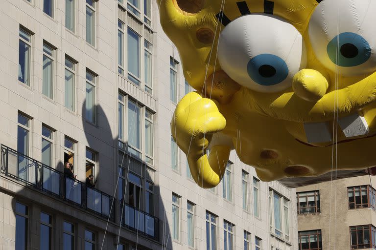 Algunas personas miran a Bob Esponja desde las ventanas durante el masivo desfile de Thanksgiving Day