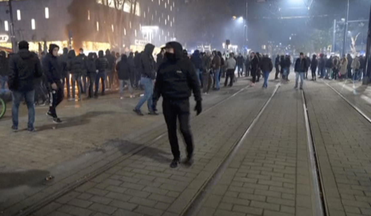 In this image taken from video, demonstrators protest against government restrictions due to the coronavirus pandemic, Friday, Nov. 19, 2021, in Rotterdam, Netherlands. Police fired warning shots, injuring an unknown number of people, as riots broke out Friday night in downtown Rotterdam at a demonstration against plans by the government to restrict access for unvaccinated people to some venues. (Media TV Rotterdam via AP)