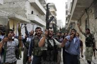 Syrian rebel fighters hold up their guns as they shout slogans in a street in the northern city of Aleppo following shelling by government forces on October 11, 2012. Arab and Western states recognised the National Coalition as the sole representative of Syrians on Wednesday, as the opposition bloc urged the US to review its blacklisting of jihadist rebels