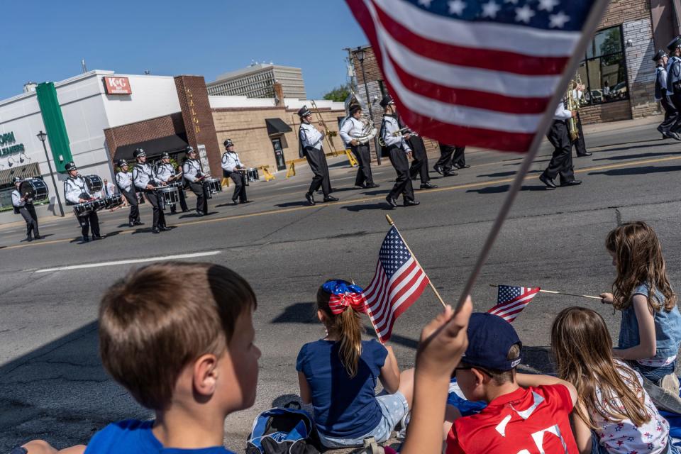 Children wave flags as members of the Edsel Ford High School marching band walk along Michigan Avenue during the 97th annual Memorial Day parade in Dearborn on Monday, May 29, 2023.