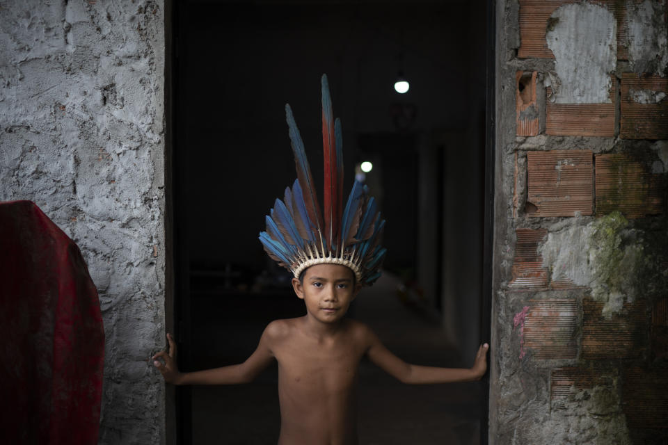 In this May 10, 2020 photo, 9-year-old Pedro Henrique poses for a photo standing in the entrance of his home at the Park of Indigenous Nations community in Manaus, Brazil, amid the new coronavirus pandemic. Some frightened residents of Manaus are fleeing but they may be asymptomatic and could spread the virus elsewhere, said the executive director of Brazil’s Institute for Health Policy Studies. (AP Photo/Felipe Dana)