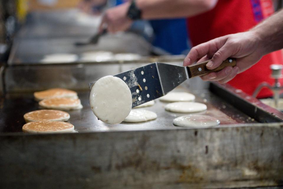 A line of volunteers make both regular and buckwheat pancakes during the Maple Syrup Festival Sunday at Bradys Run Park.