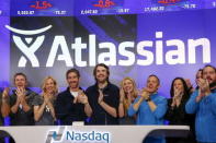 Mike Cannon-Brookes (C), co-founder and CEO of Atlassian Software Systems, and Scott Farquhar (3rd L), co-founder and CEO of Atlassian Software Systems, smile during it's opening PO at the Nasdaq at a MarketSite in New York, December 10, 2015. REUTERS/Shannon Stapleton