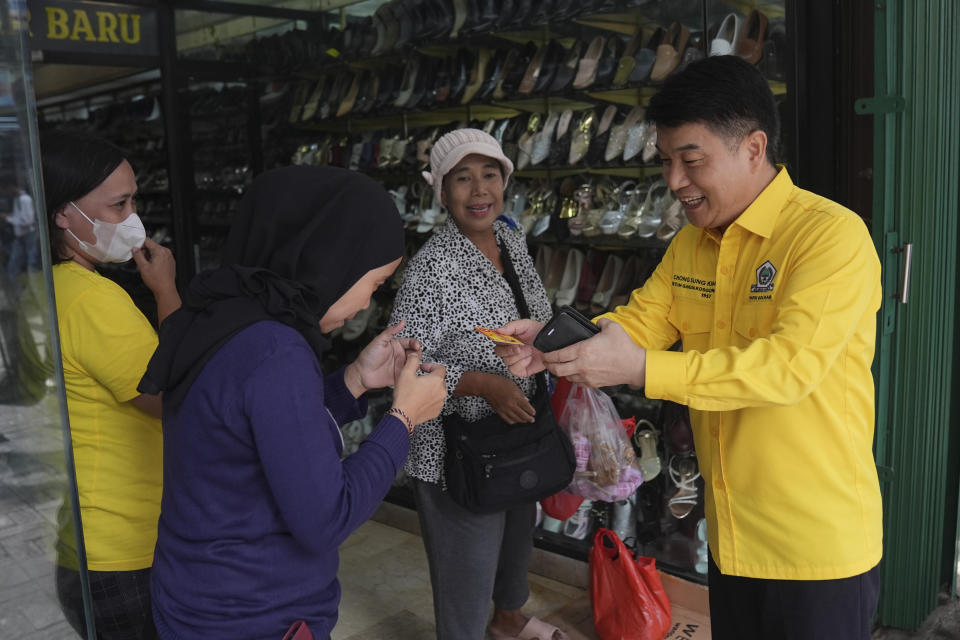 Chong Sung Kim, a Golongan Karya party legislative candidate, hands out his cards to shop attendants during his campaign at a shopping center in Jakarta, Indonesia, Tuesday, Jan. 30, 2024. As Indonesia votes this month to replace popular President Joko Widodo, all three candidates have all been aggressively seeking to win the votes of younger people, reaching out to them on the apps they use, through the K-pop music many love, and even video gaming events. (AP Photo/Dita Alangkara)