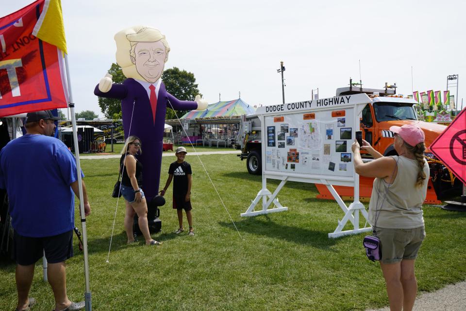 Visitors take a picture with an inflatable figure of former President Donald Trump at the Dodge County Fair on Friday, Aug. 18, 2023.