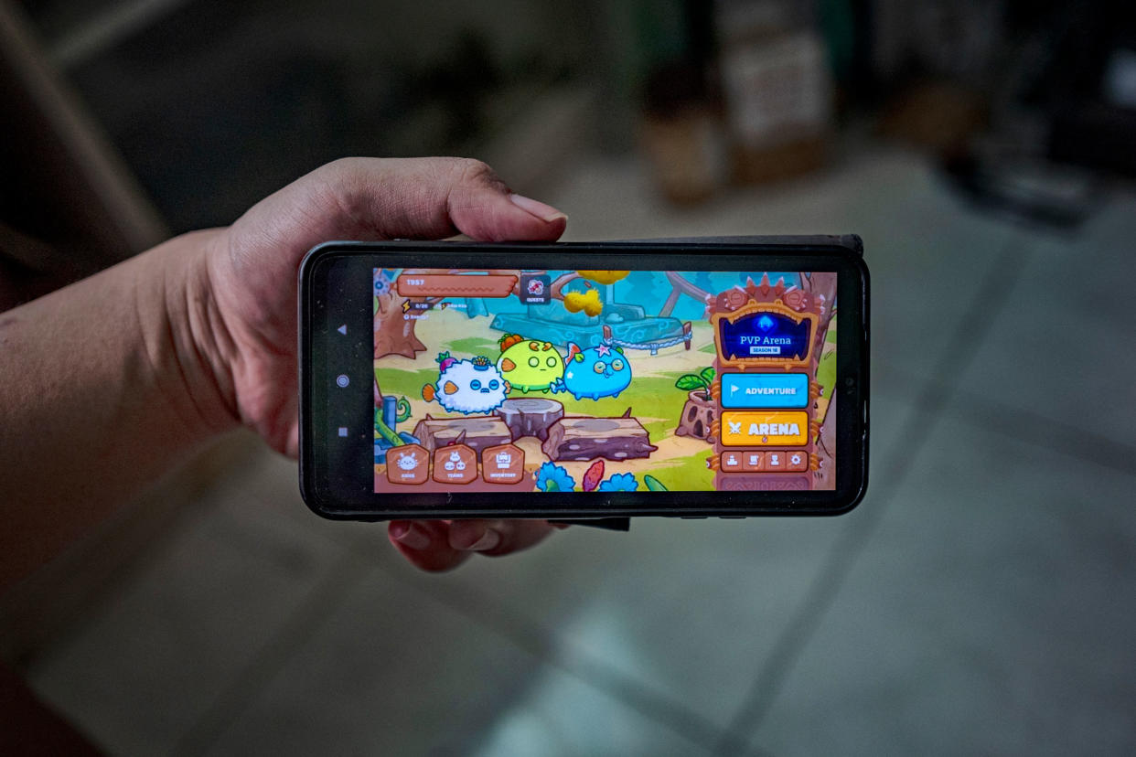 a hand holding a phone playing Axie Infinity