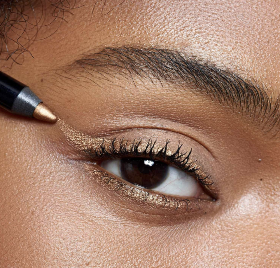 black model with brown eyes close up wearing CASA ZETA-JONES Eye Contact Long-Lasting Pencil Eyeliner in Gilda Gold 