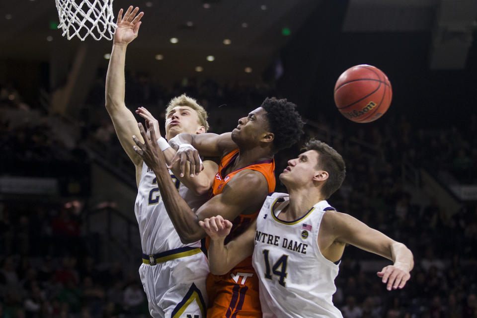 Notre Dame's Dane Goodwin, left, and Nate Laszewski (14) compete for a rebound with Virginia Tech's John Ojiako during the first half of an NCAA college basketball game Saturday, March 7, 2020, in South Bend, Ind. (AP Photo/Robert Franklin)