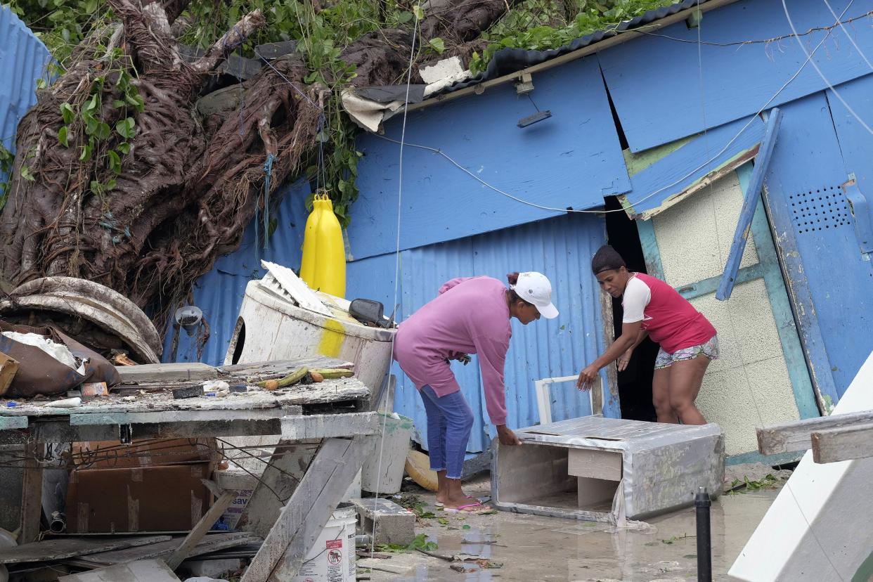Yesenia Martinez, left, and Dilcia Figaro pick up items scattered by Hurricane Fiona in the low-income neighborhood of Kosovo in Veron de Punta Cana, Dominican Republic, Monday, Sept. 19, 2022.