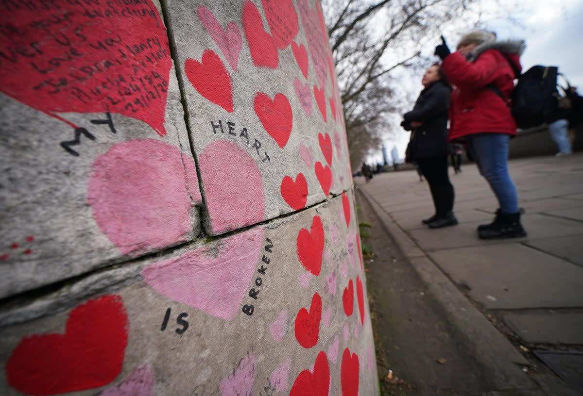 People look at tributes on the Covid memorial wall in central London (Yui Mok/PA) (PA Wire)