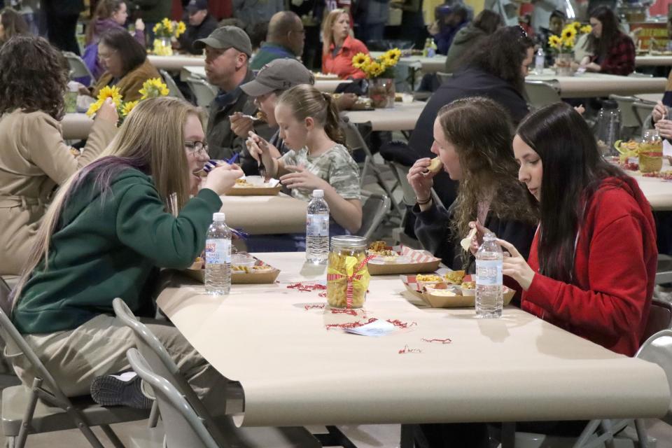 Trystan Lyons, McKenzie Bryant and Devyn Benavidez enjoy the varity of samples of mac and cheese at the Hope and Healing Place's annual The Big Cheese macaroni and cheese competition at the Rex Baxter Building Friday evening.