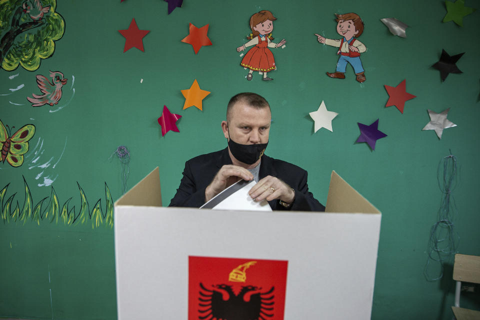 An Albanian man casts folds his ballot during parliamentary elections in capital Tirana, Albania, Sunday, April 25, 2021. Albanian voters have started casting ballots in parliamentary elections on Sunday amid the virus pandemic and a bitter political rivalry between the country's two largest political parties. (AP Photo/Visar Kryeziu)